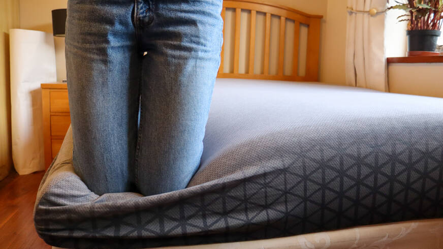kneeling on the side of the zoma mattress